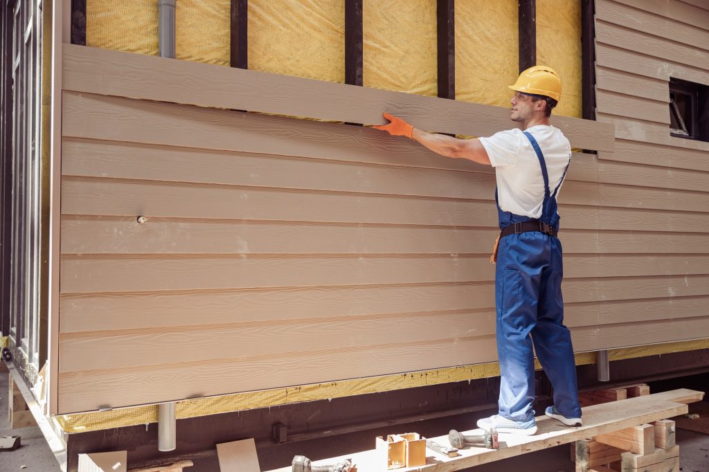 Handsome man builder building cabin at construction site
